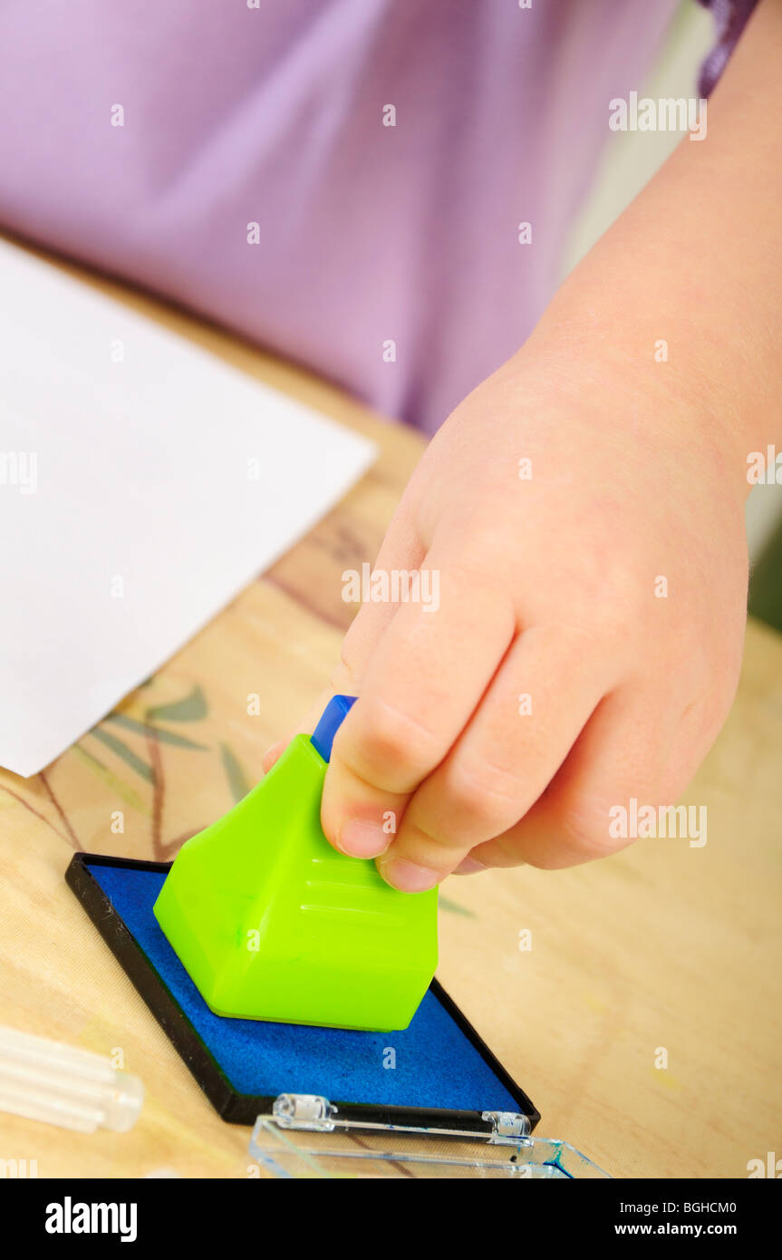 Foto di stock di un 4 anno vecchia ragazza utilizzando inchiostro timbri durante un gioco creativo sessione. Foto Stock