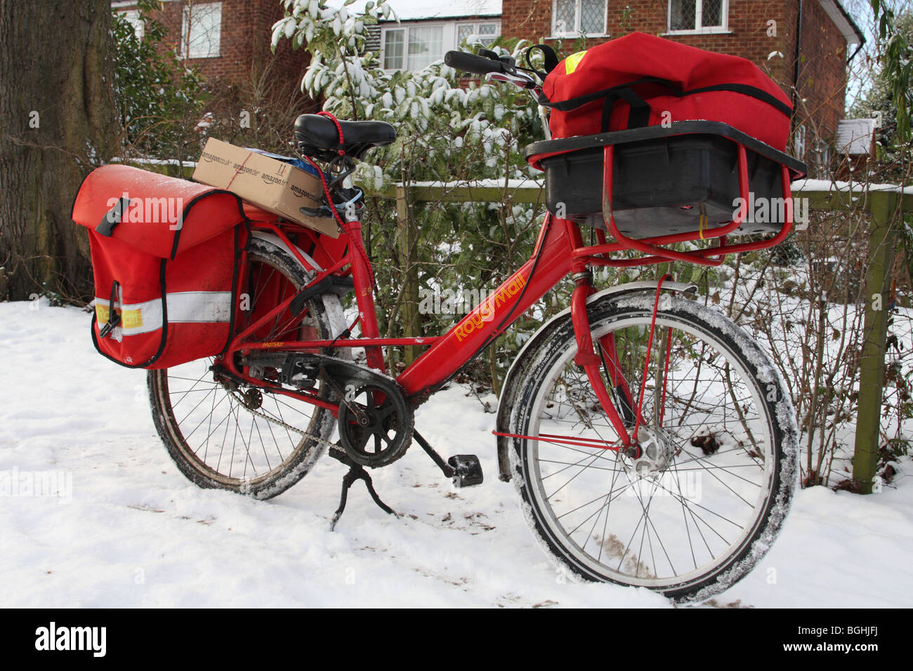 Un Royal Mail in bicicletta in un villaggio Inglese in inverno. Foto Stock