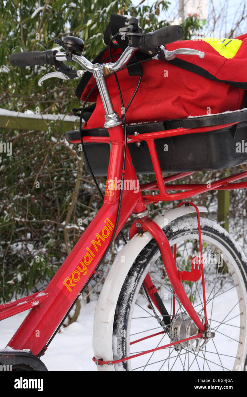 Un Royal Mail in bicicletta in un villaggio Inglese in inverno. Foto Stock