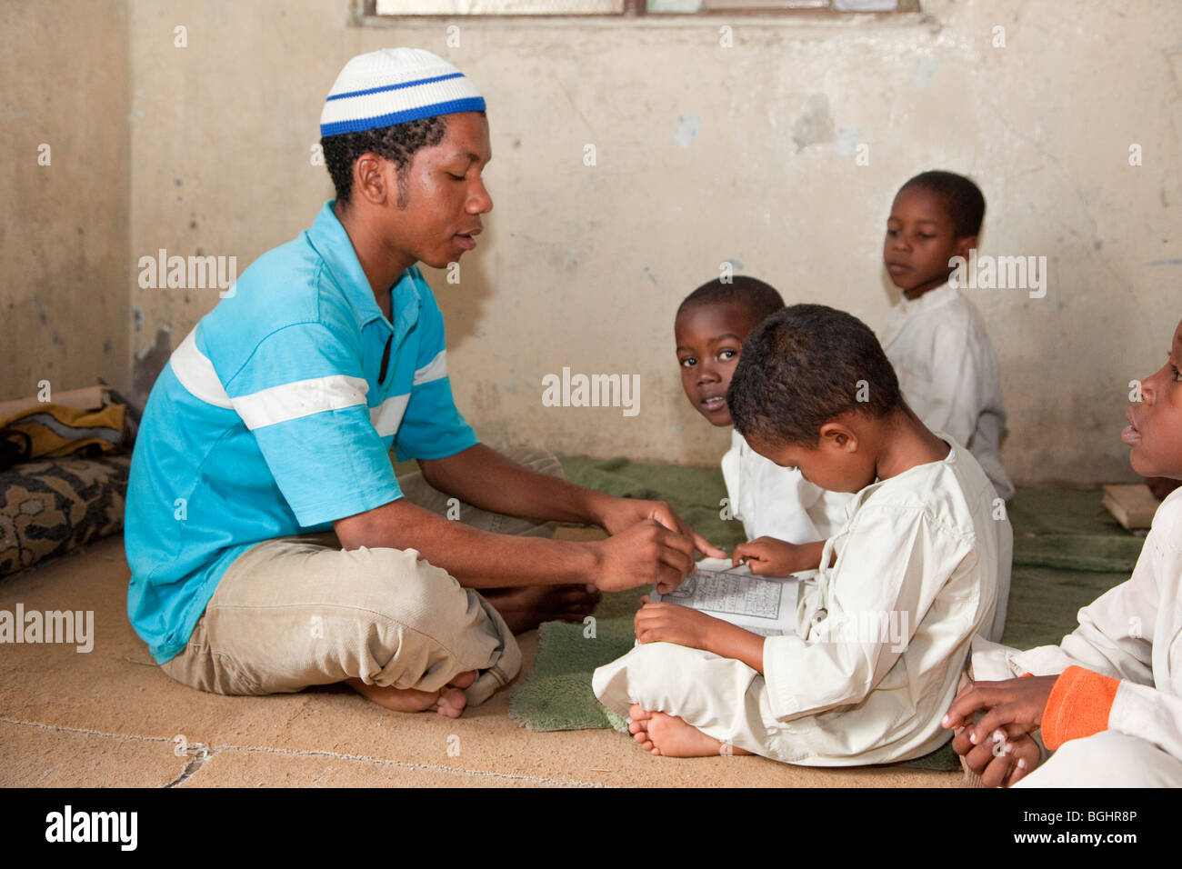 Zanzibar, Tanzania. L Imam in una madrassa (scuola coranica) insegnare ai giovani un ragazzo a leggere le lettere dell'alfabeto arabo. Foto Stock