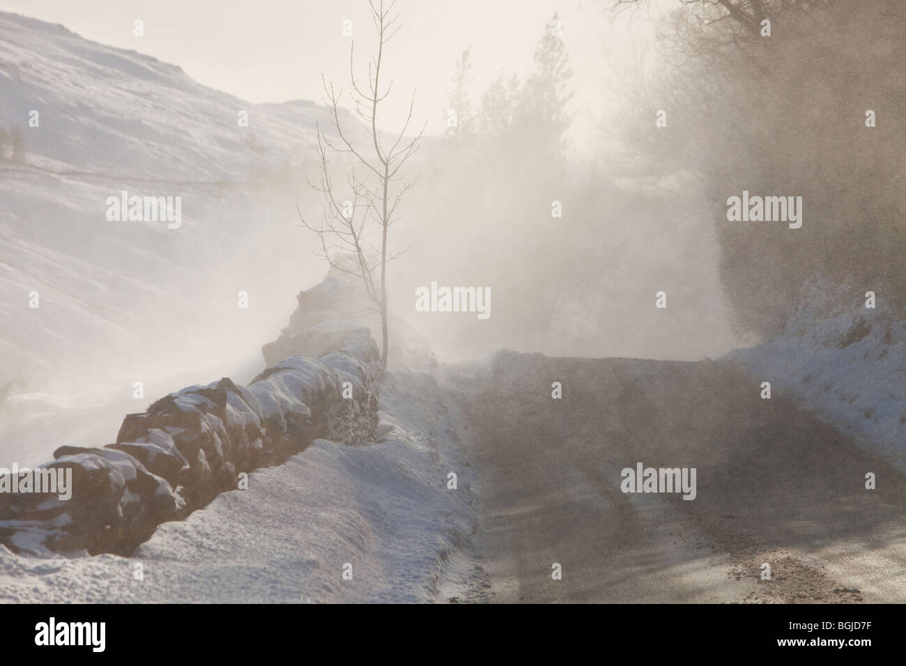 Il Kirkstone pass road al di sopra di Windermere è bloccato da spindrift e soffiata dal vento, neve Lake District, UK. Foto Stock