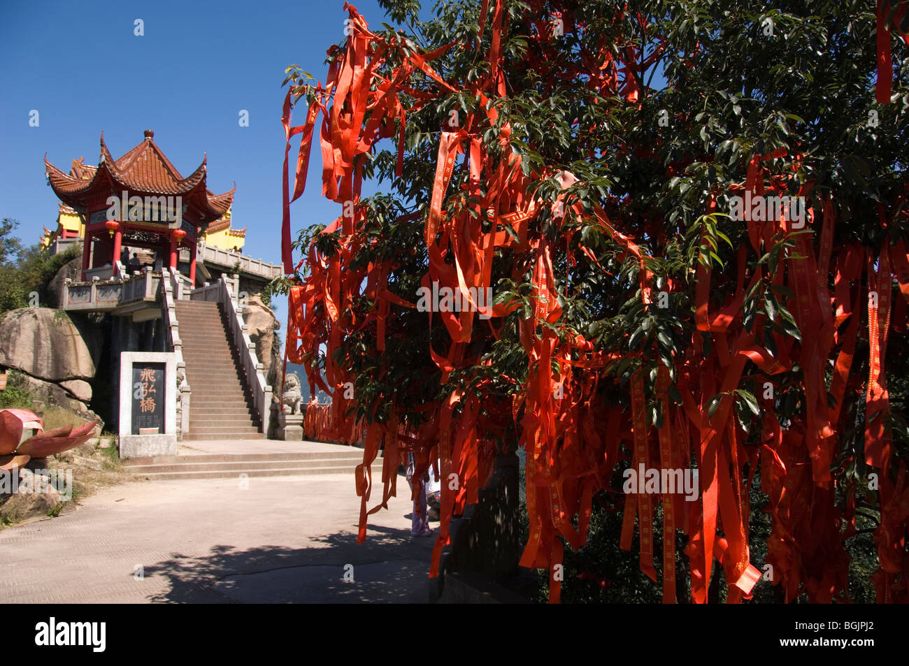 Rosso nastri di preghiera in un albero vicino a un buddista padiglione sul Jiuhua Shan. Provincia di Anhui, Cina. Foto Stock