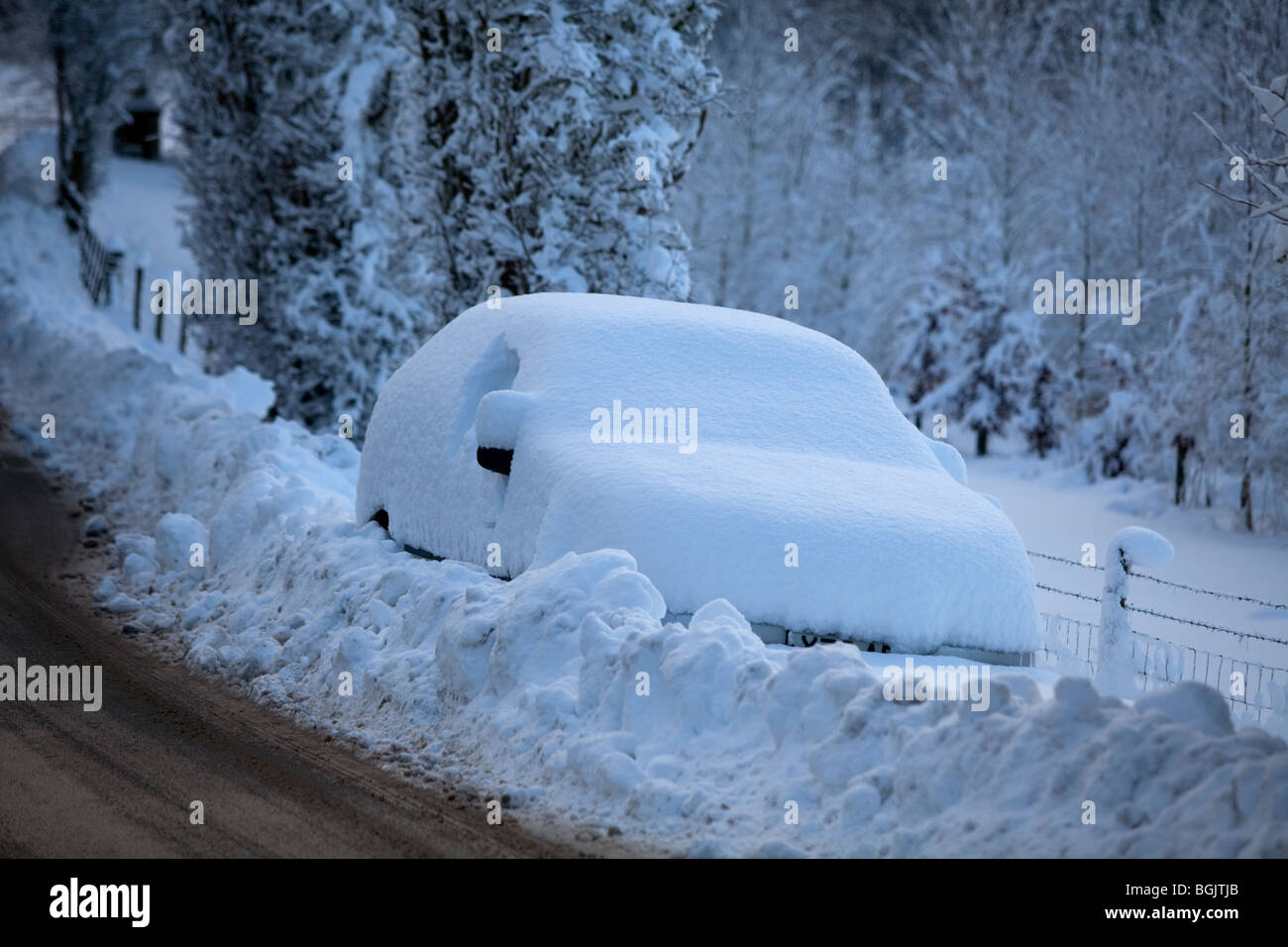 Un filamento auto nella neve con il lato di una strada a Broadway, Worcestershire, Regno Unito Foto Stock