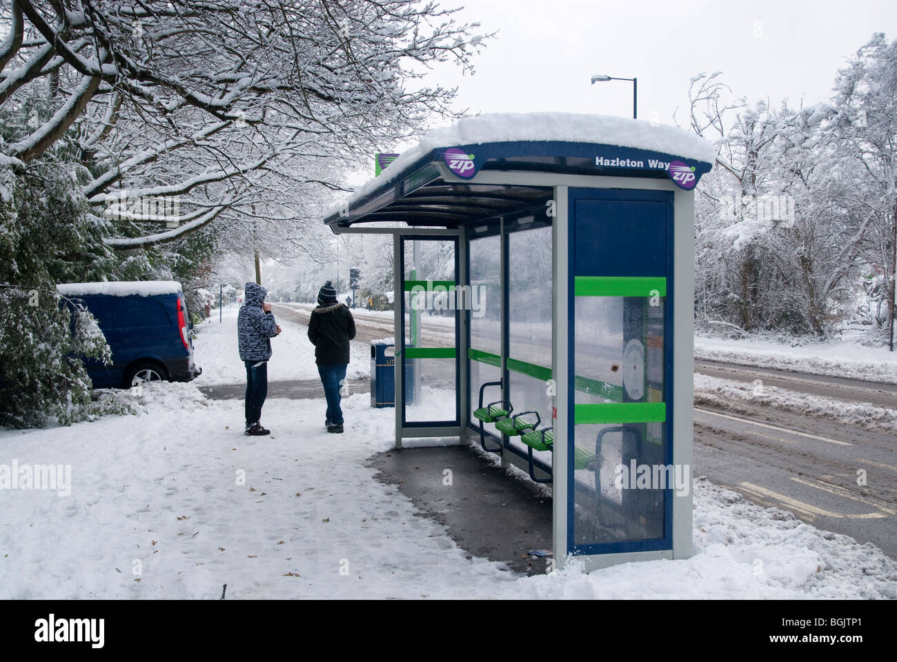 Due persone in attesa alla coperta di neve fermata bus quando nessun autobus che corrono. Grande neve caduta A3 area di hampshire gennaio 2010 Foto Stock