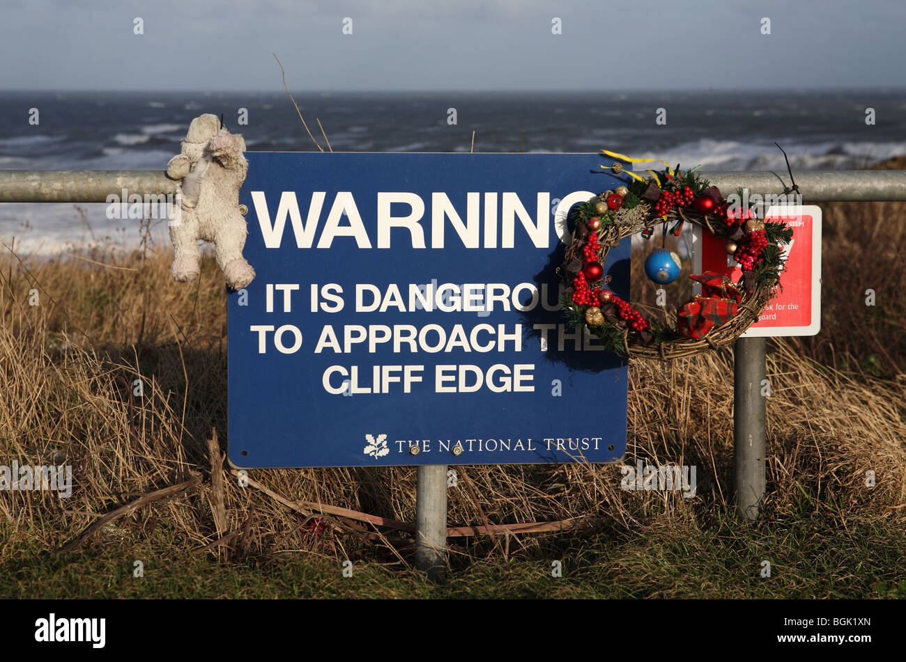 Cliff cartello segnaletico adornata con una ghirlanda e orsacchiotto prese a Marsden, Tyne and Wear. Foto Stock