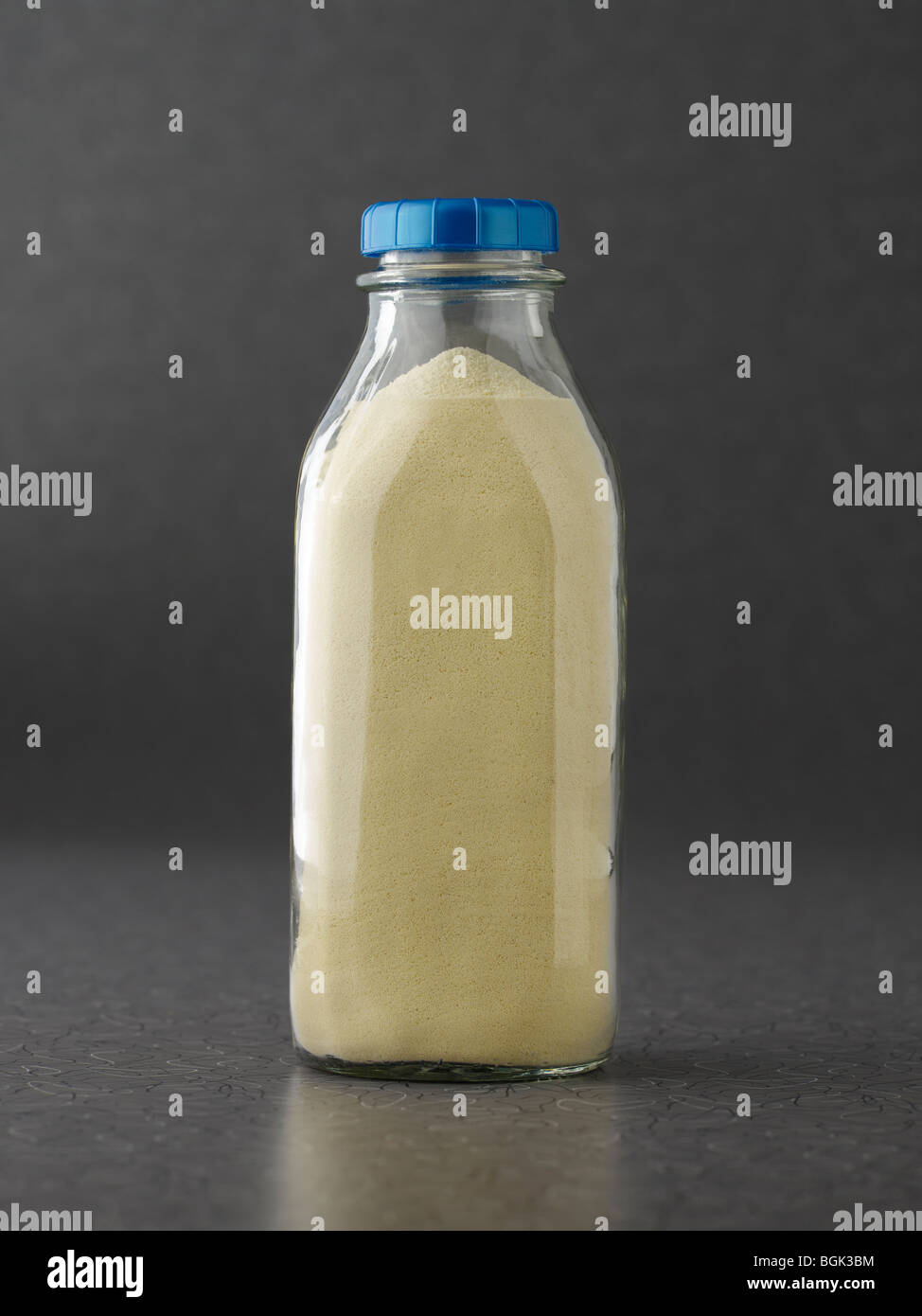 Proteina di latte in polvere nella bottiglia di latte su sfondo grigio Foto Stock