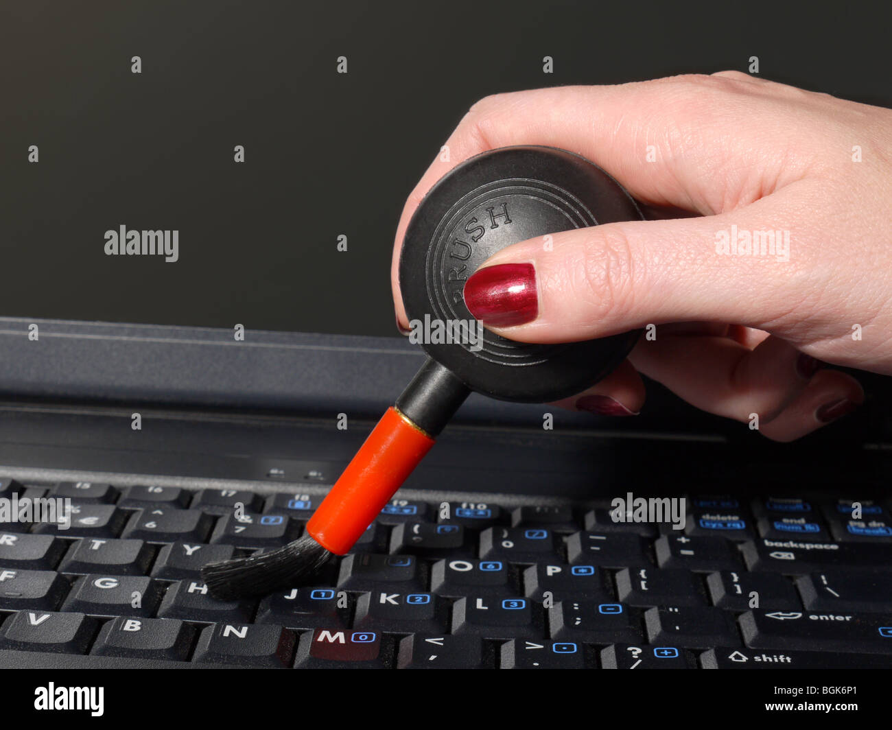 Closeup colpo di mano femmina spazzare la polvere dalla tastiera laptop utilizzando aria lampadina Foto Stock