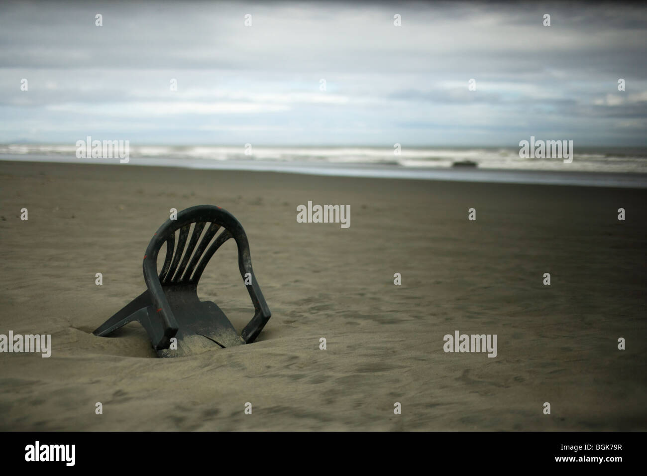 Sedia in plastica sulla spiaggia deserta, Nuova Zelanda Foto Stock