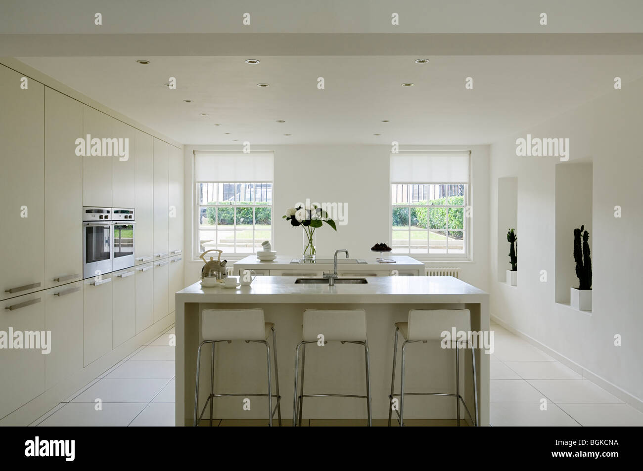 Cucina minimalista in bianco con barstools e isola Foto Stock