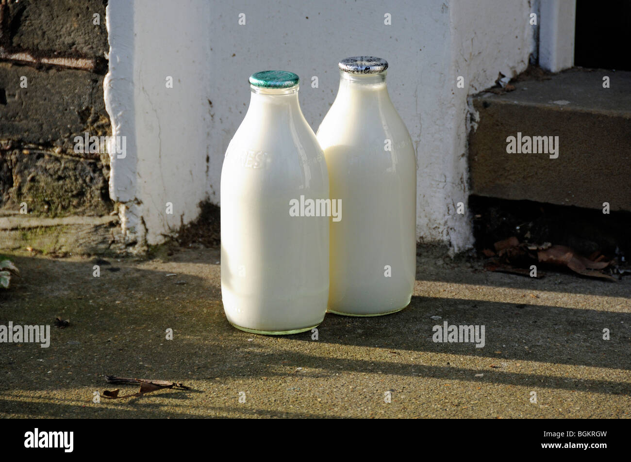 Due bottiglie di latte da pinta a portata di mano, una con tappo verde e una argento, Londra Inghilterra Gran Bretagna, Regno Unito, rifiuti zero Foto Stock