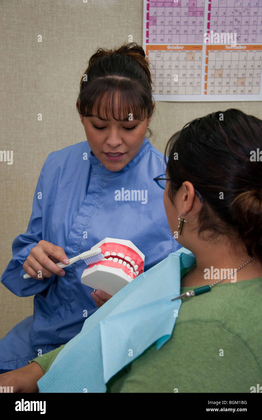 Native American Dental hygenist dimostra il corretto spazzolamento dei denti e la salute di un elemento tribale paziente presso la clinica di Montana Foto Stock