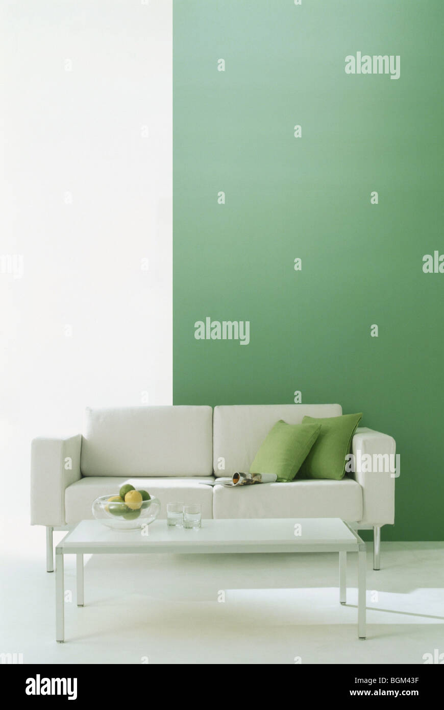 Divano e tavolo da caffè in camera con parete verde Foto Stock
