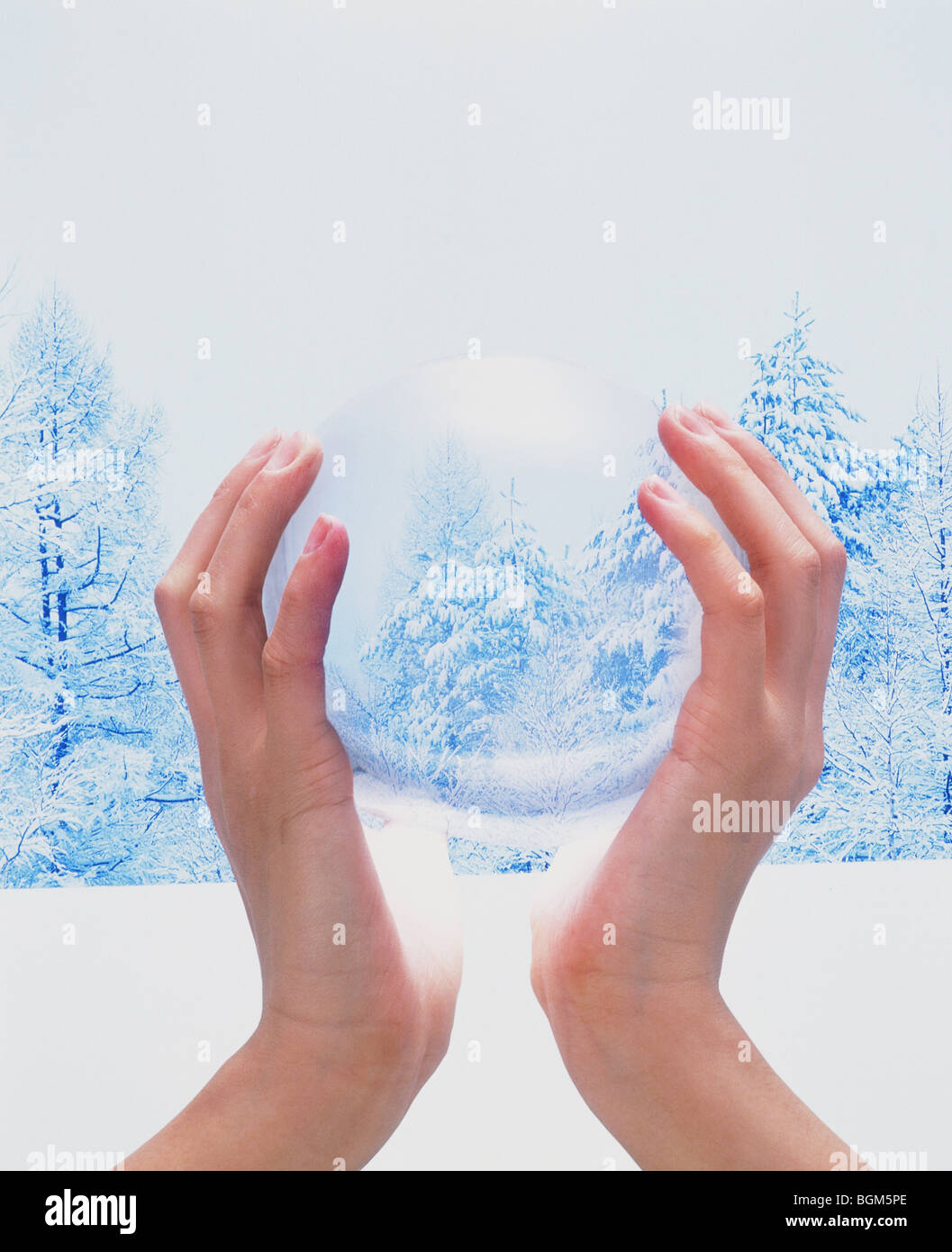 Mani cullano sfera di cristallo nel paesaggio invernale Foto Stock