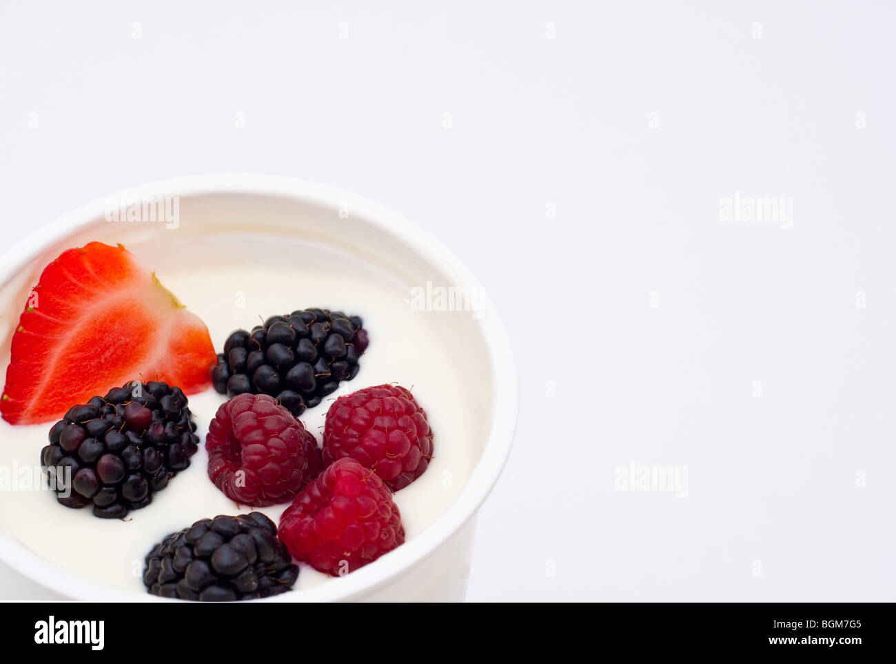 Frutti di bosco immerso nella naturale yogurt greco Foto Stock