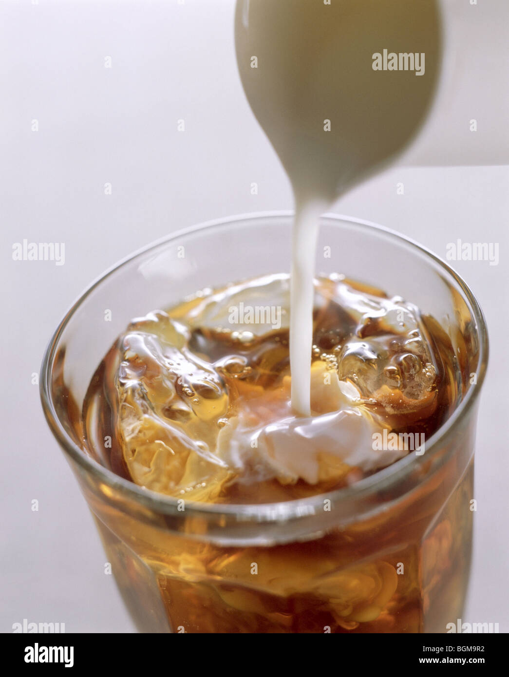 Il latte che viene versato in ghiaccio tè Foto Stock