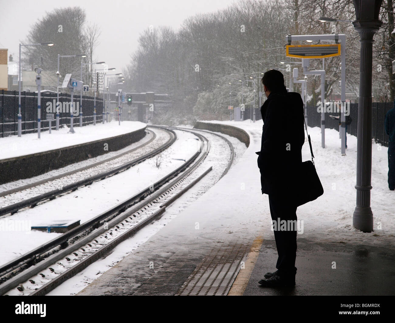" Commuter " in attesa di un treno in ritardo da neve in una ferrovia suburbana stazione al di fuori di Londra. Foto Stock