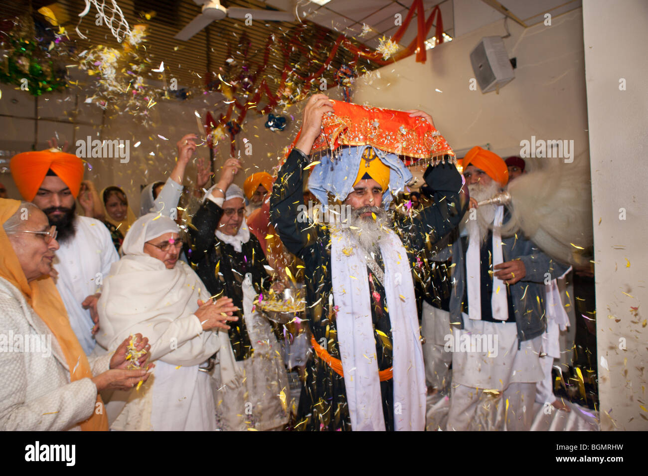 Le donne di gettare petali di fiori come il Guru Granth Sahib è portato dalla sala culto per la processione Vaisakhi Foto Stock