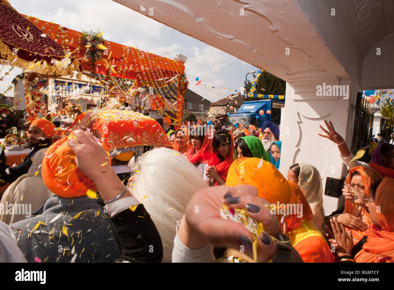 Le donne di gettare petali di fiori come il Guru Granth Sahib è portato dal Gurdwara un galleggiante per la processione Vaisakhi Foto Stock