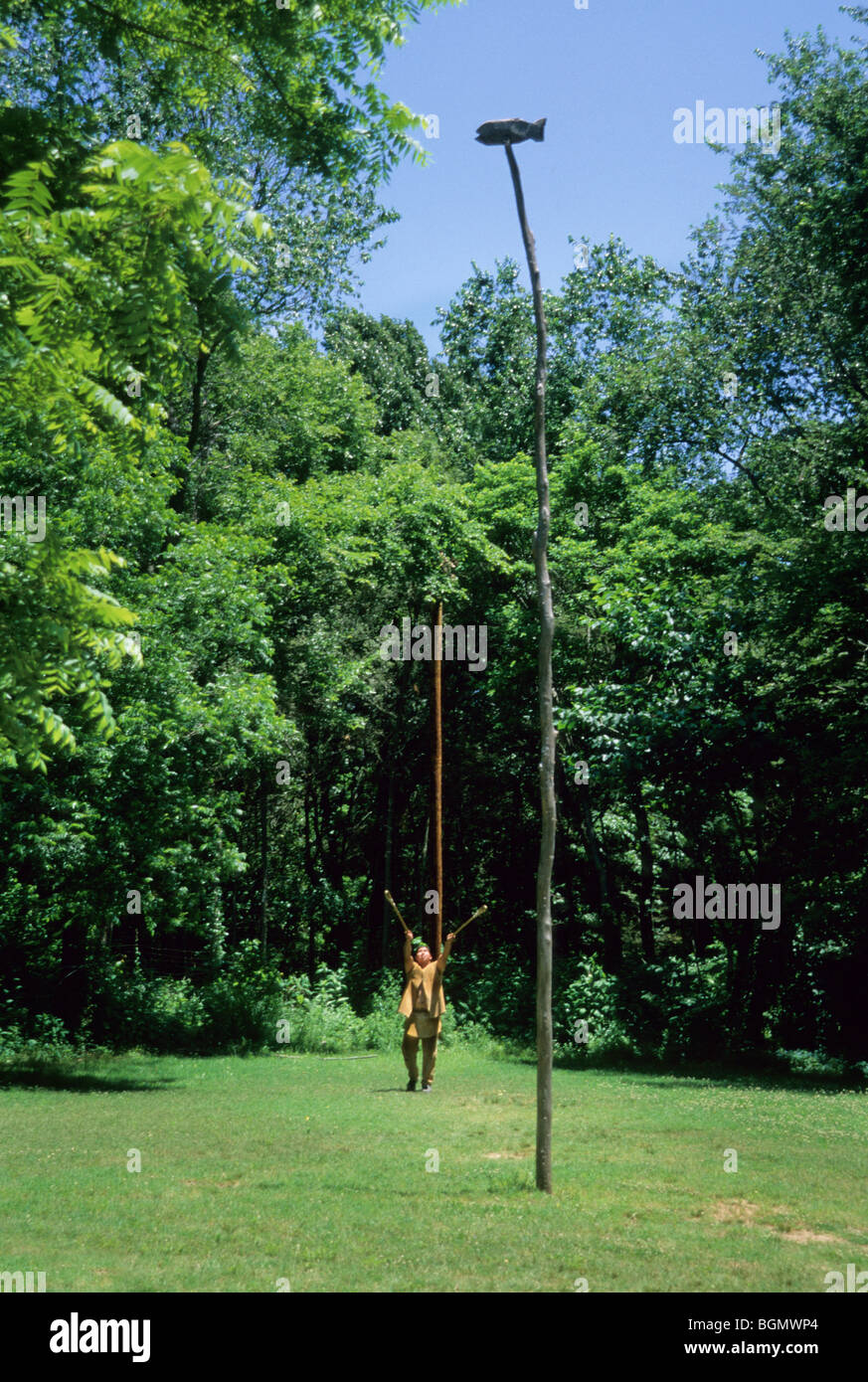 L'uomo Cherokee vestito con abiti tradizionali in pelle di cervo dimostra la partita di stickball al Cherokee Indian Village di Tahlequah Oklahoma Foto Stock