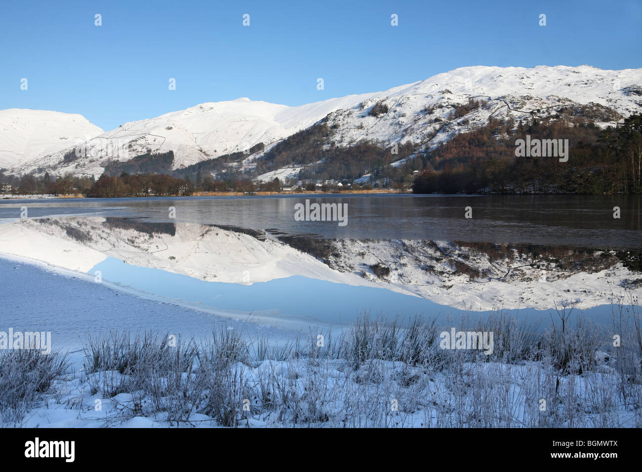 Grasmere con neve rivestiti montagne riflesse nel lago, Cumbria, Regno Unito Foto Stock