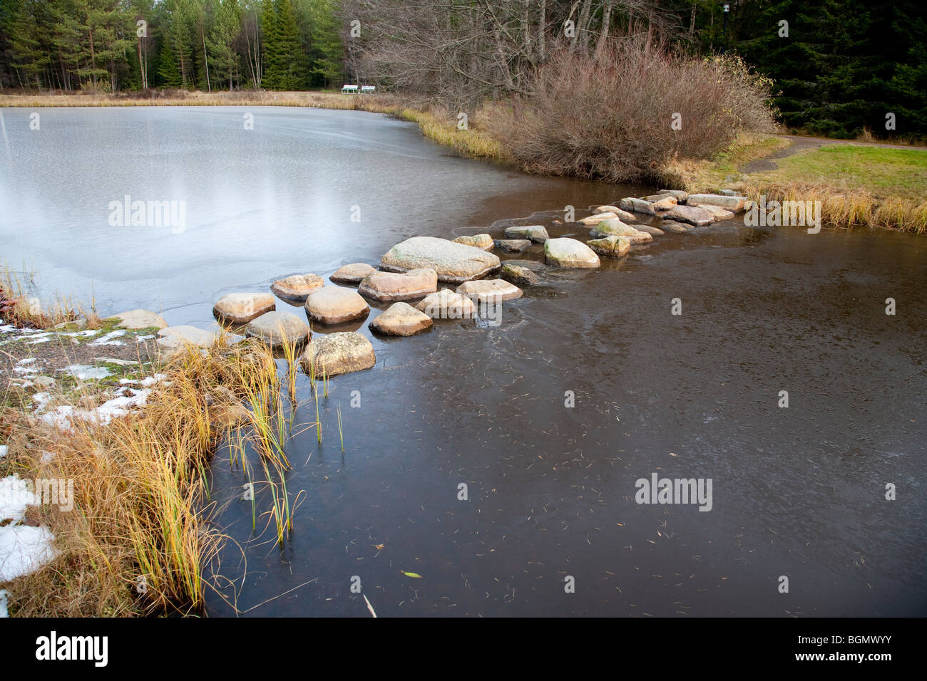 Stepping di pietre sopra un laghetto ghiacciato, Finlandia Foto Stock