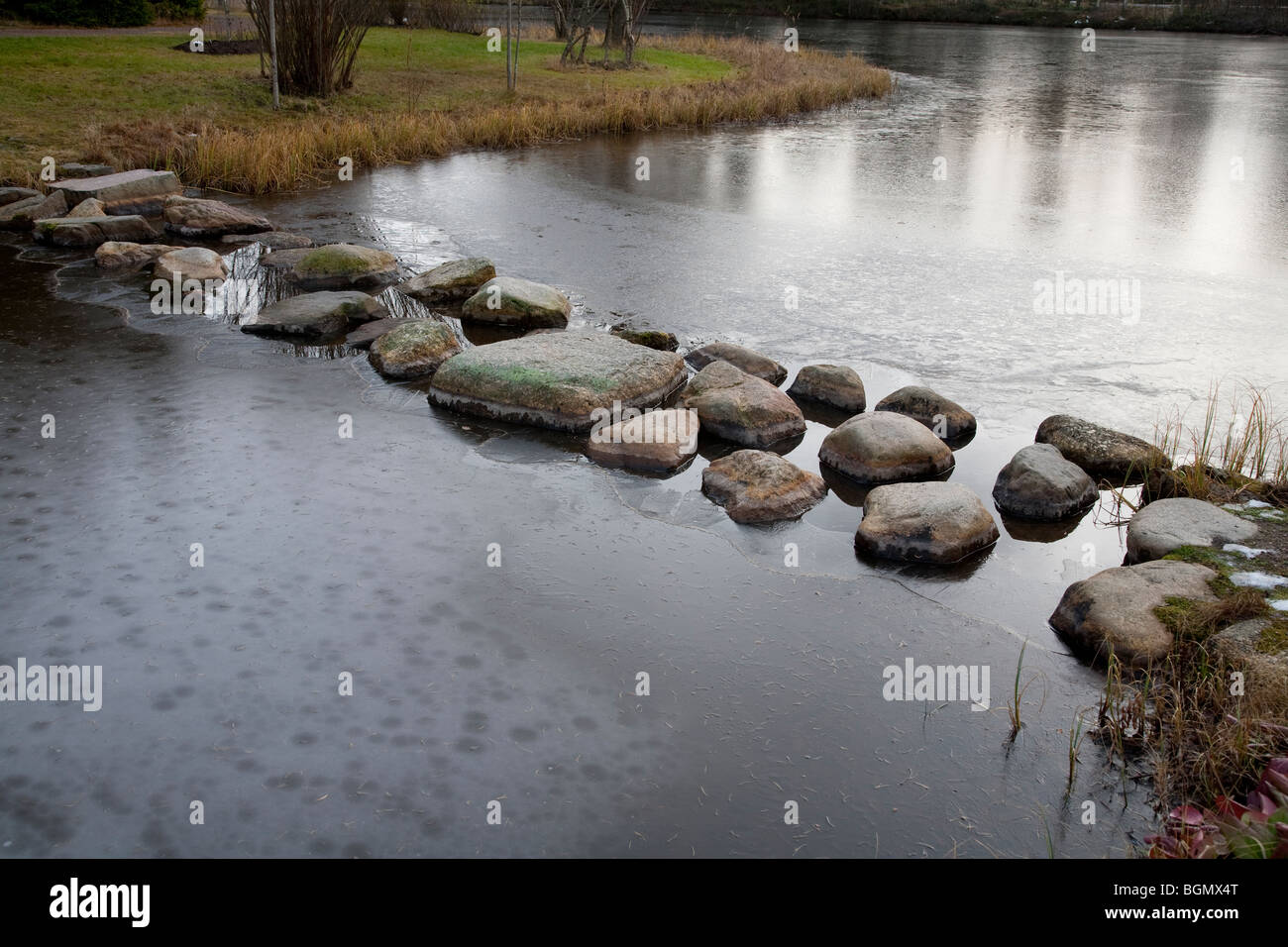 Stepping di pietre sopra un laghetto ghiacciato, Finlandia Foto Stock