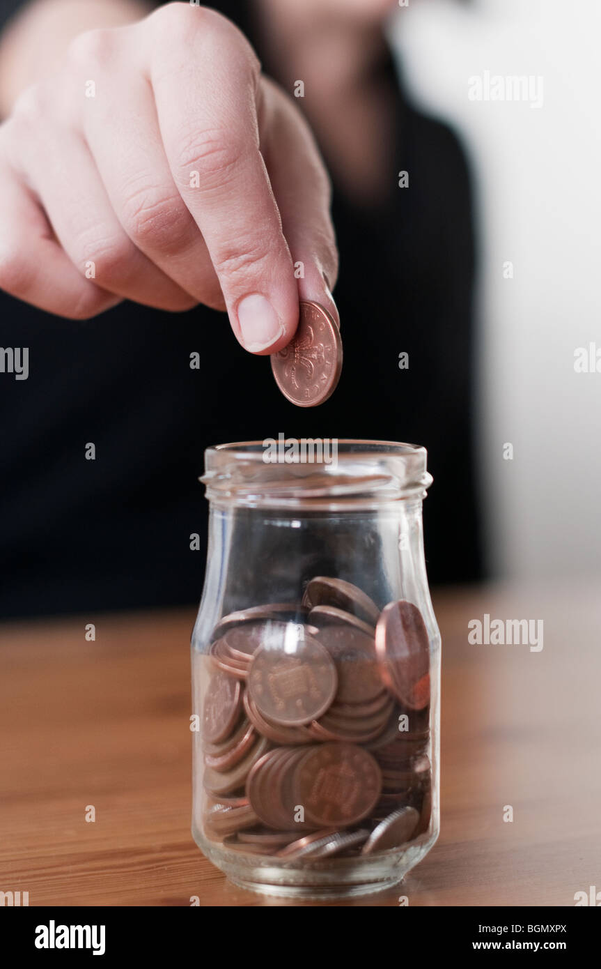 Persona scende una moneta nel vaso di raccolta Foto Stock