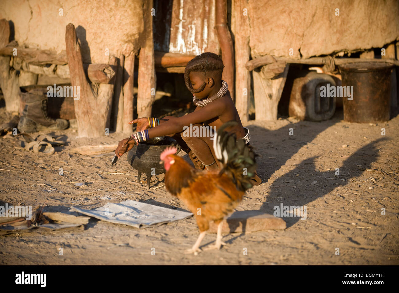 Ragazzo Himba cucinando fuori la sua capanna, Kaokoland, Namibia Foto Stock