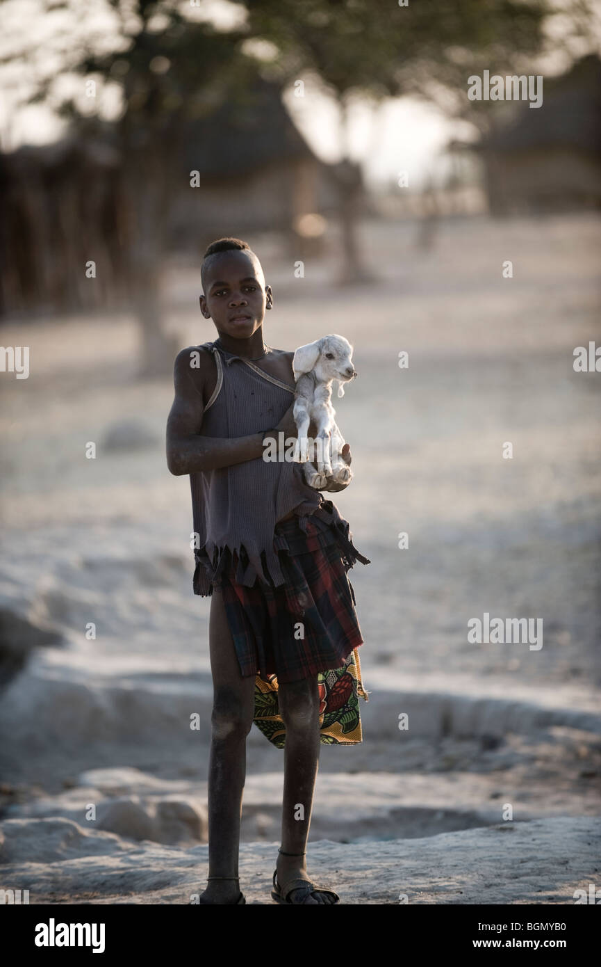 Giovane ragazzo Himba tendente alla sua famiglia capre Foto Stock