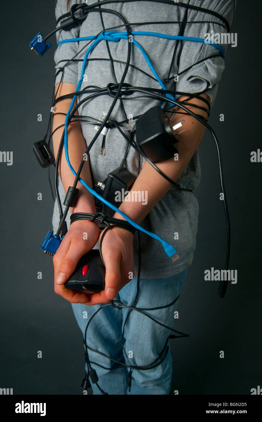 Adolescente con i capelli lunghi legati a cavi per computer che simboleggiano l'essere vincolato alla tecnologia Foto Stock