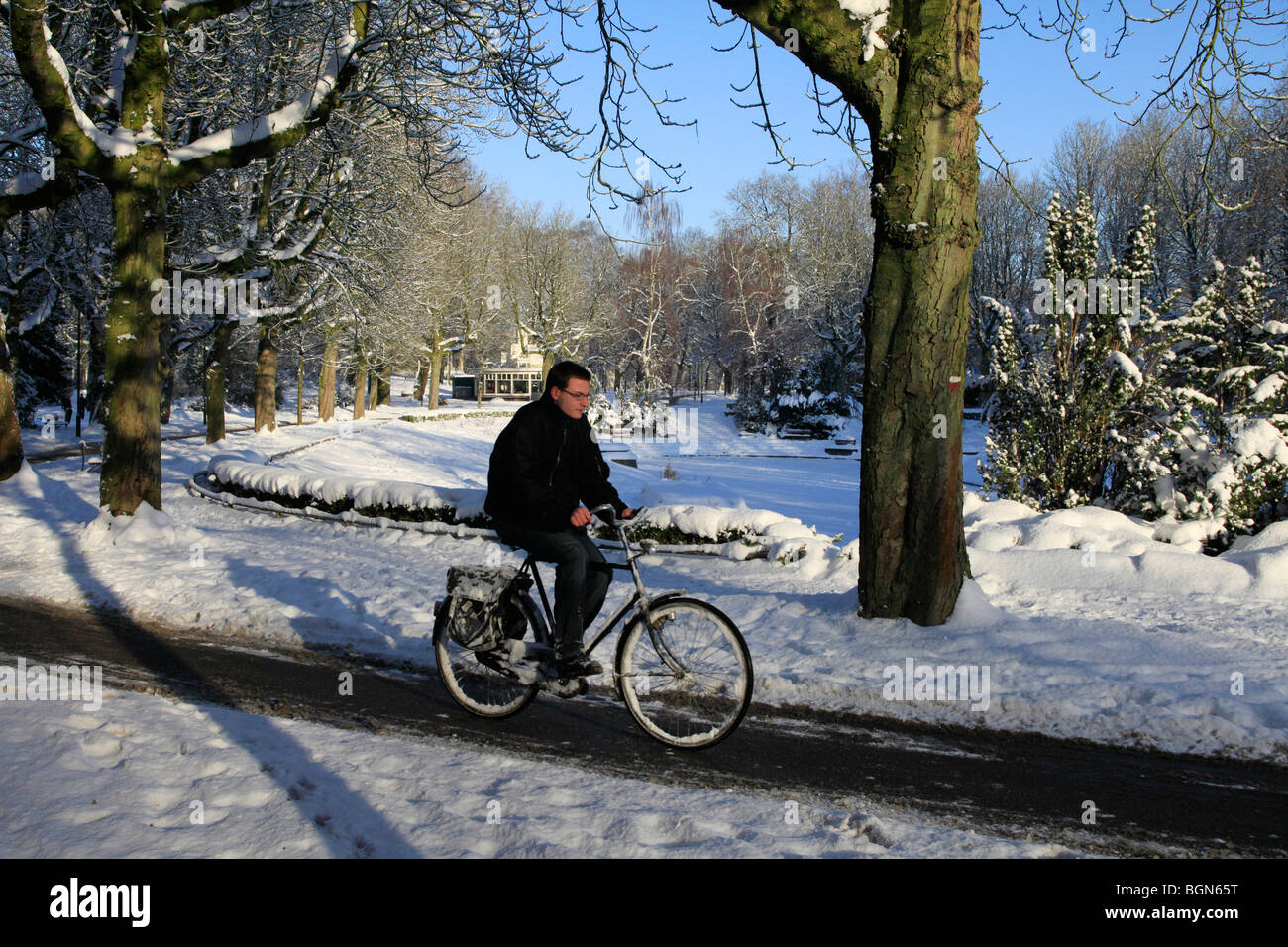 Uomo in bici attraverso il paesaggio invernale con la neve Foto Stock