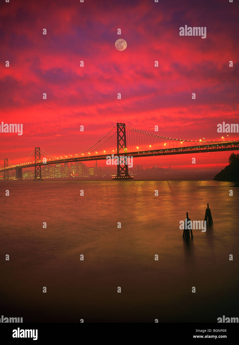 Oakland Bay Bridge di San Francisco Bay sotto la luna piena drammatico tramonto rosso del cielo Foto Stock