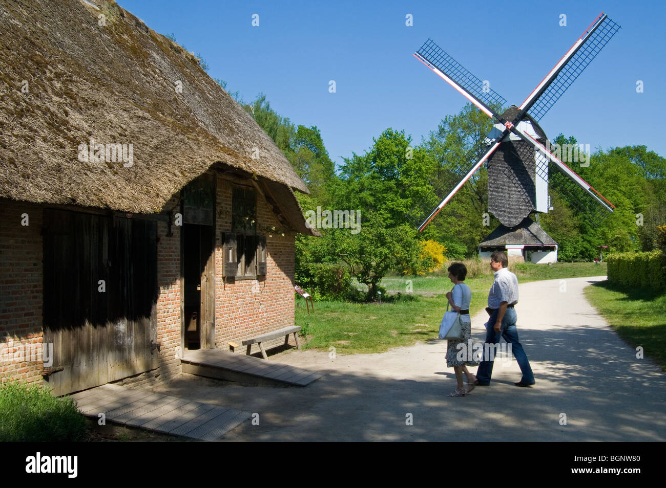 Il mulino a vento Standerd e i turisti in visita a una tradizionale casa colonica presso l'open air museum Bokrijk, Belgio Foto Stock