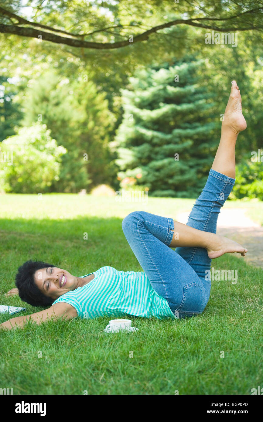Donna matura sdraiati sull'erba e di esercizio Foto Stock