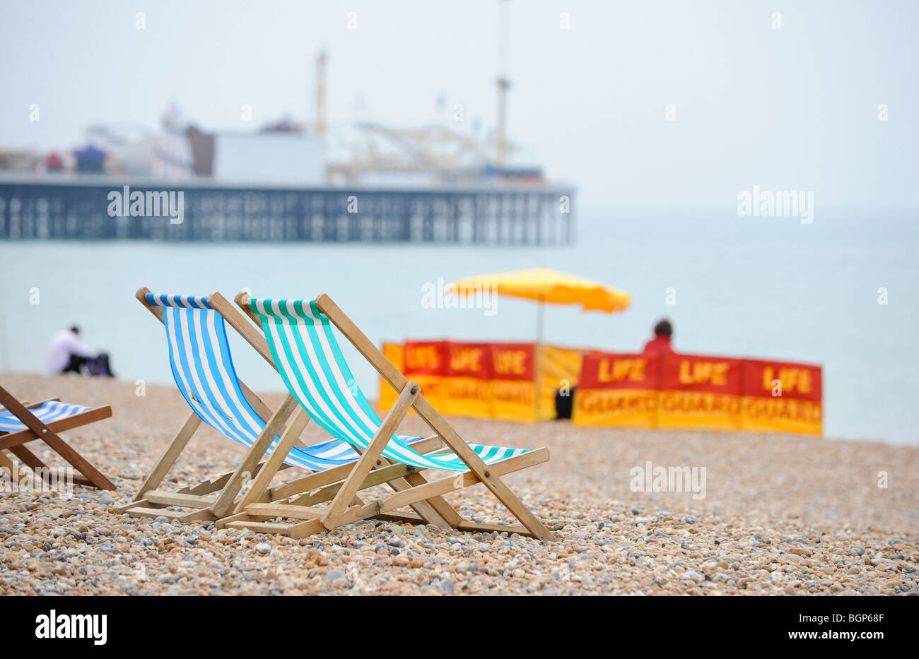 Sicurezza spiaggia sulla spiaggia di Brighton in East Sussex. Sedie a sdraio sulla spiaggia con una vita stazione di guardia in distanza. Foto Stock