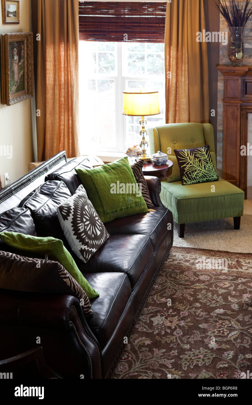In pelle marrone scura con lettino verde acido poltrona tavolino con lampada dalla finestra in una contemporanea americana stanza vivente Foto Stock