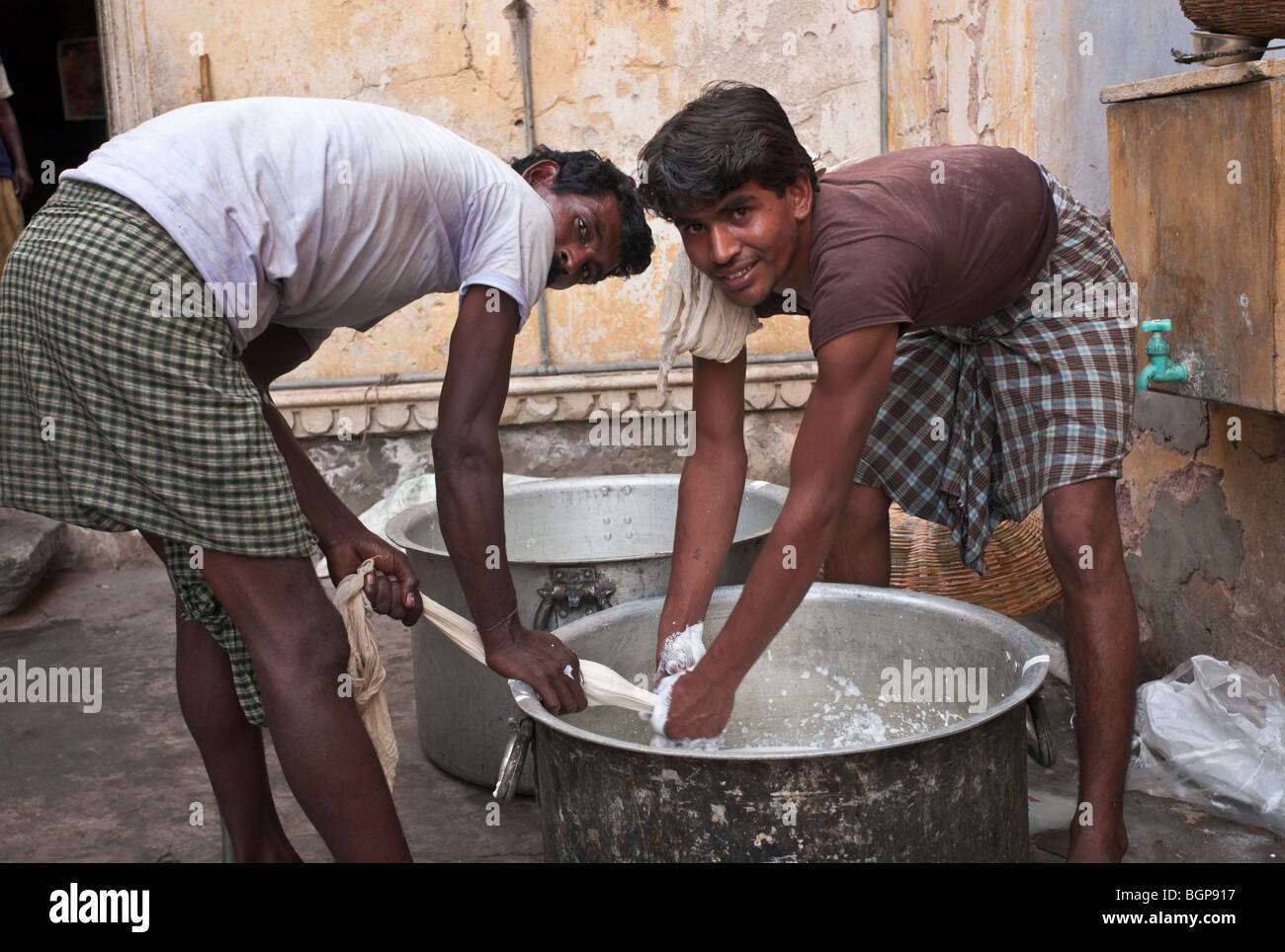 Due uomini la preparazione di solidi di latte per la cottura in un tempio indù per carità, Jaipur, India. Foto Stock