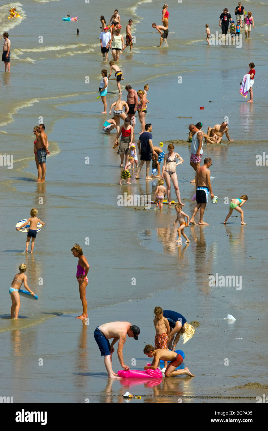 I turisti in costume da bagno sulla spiaggia sguazzare nel Mare del Nord in una giornata calda durante le vacanze estive Foto Stock