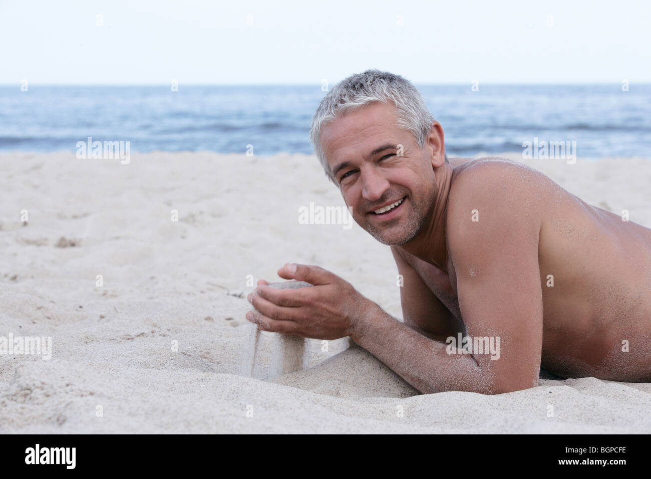Uomo Bello Con Sabbia In Mani Sdraiato Sulla Spiaggia Foto Stock Alamy