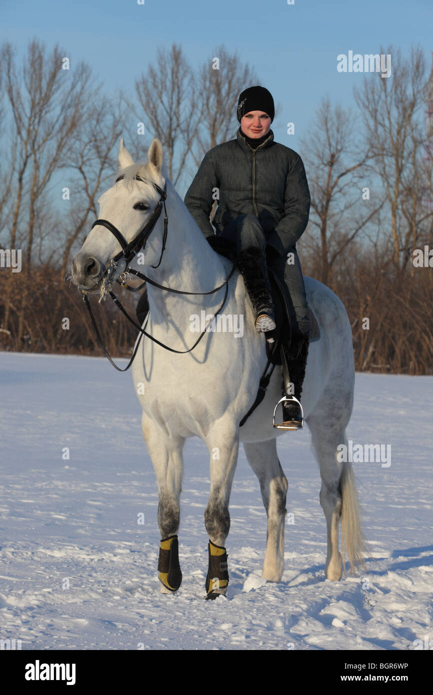 Giovane pilota sedersi sulla schiena del cavallo al ranch di inverno Foto Stock