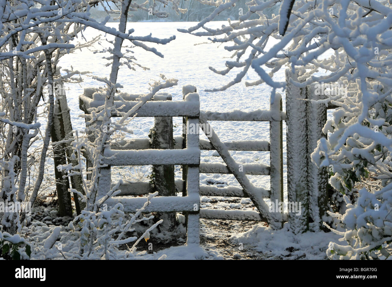 Coperta di neve sentiero pubblico con kissing gate entrando in campo gli agricoltori Foto Stock