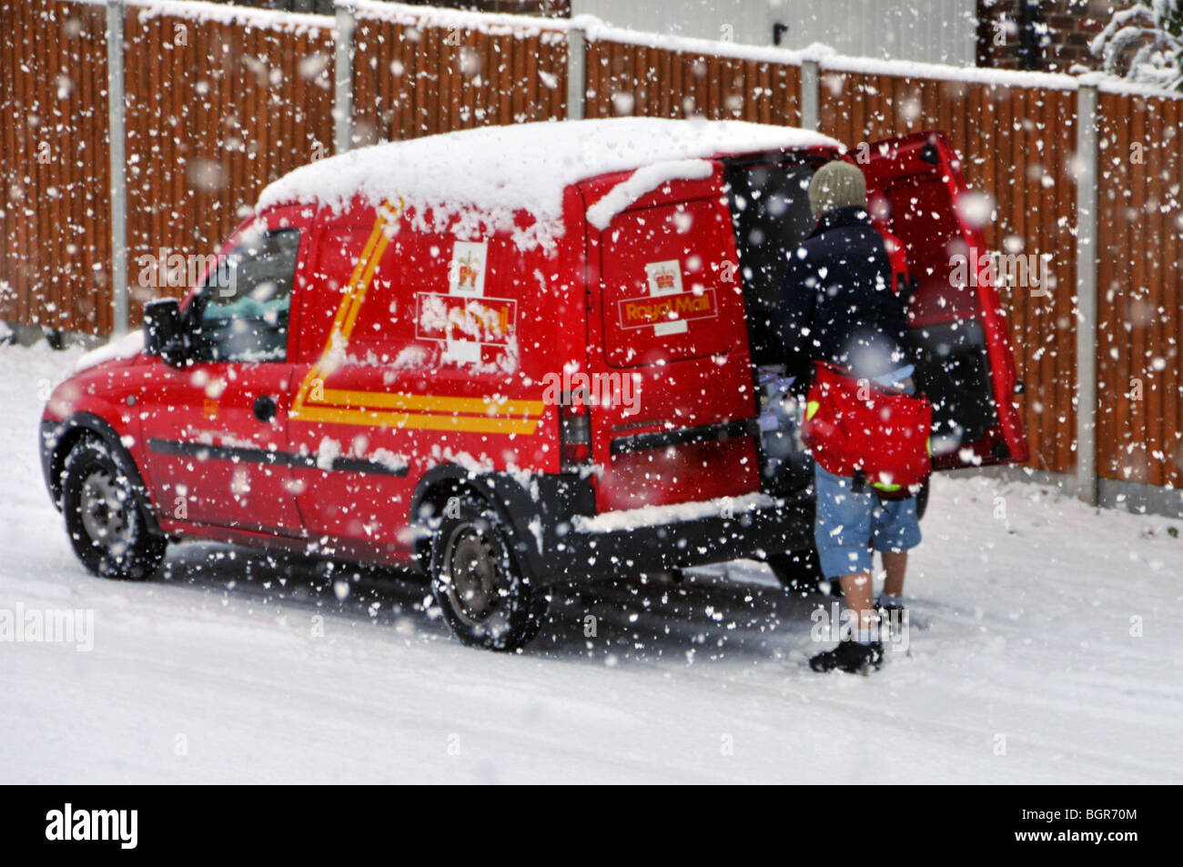 Inverno freddo scena nevicando sulla posta reale consegna postman lavoro da post van in strada residenziale in tempesta di neve Brentwood Essex Inghilterra Regno Unito Foto Stock