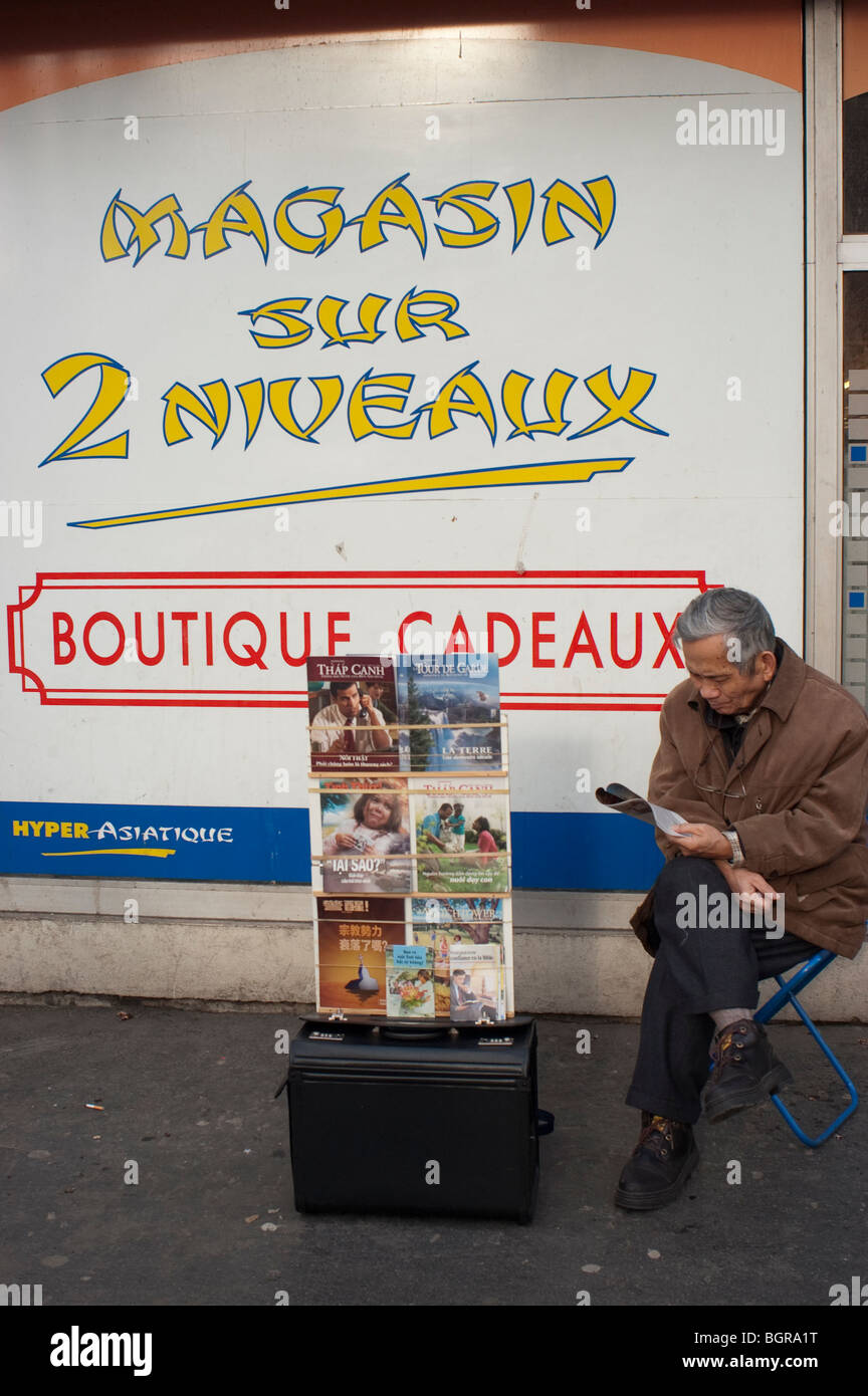 Parigi, Francia, Street Scene, Chinatown, Asian Man Raising Money for Religious Group, Jehovah Witnesses, di fronte al cartello pubblicitario sul muro Foto Stock