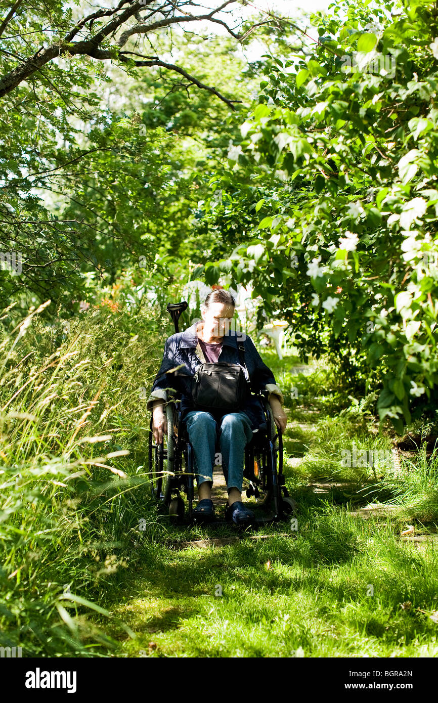 La donna in sedia a rotelle in giardino Foto Stock