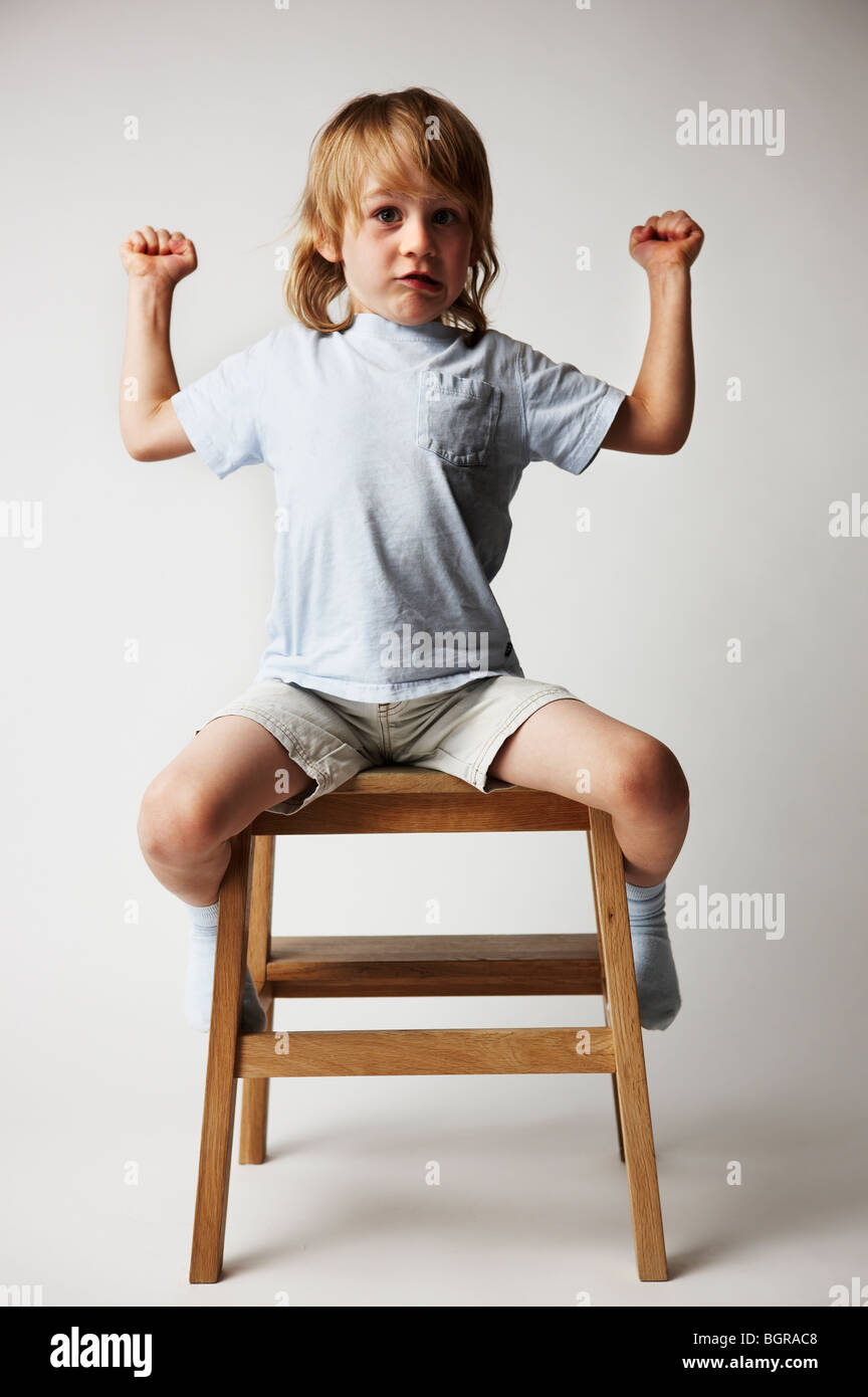 Ritratto di un ragazzo seduto su uno sgabello. Foto Stock