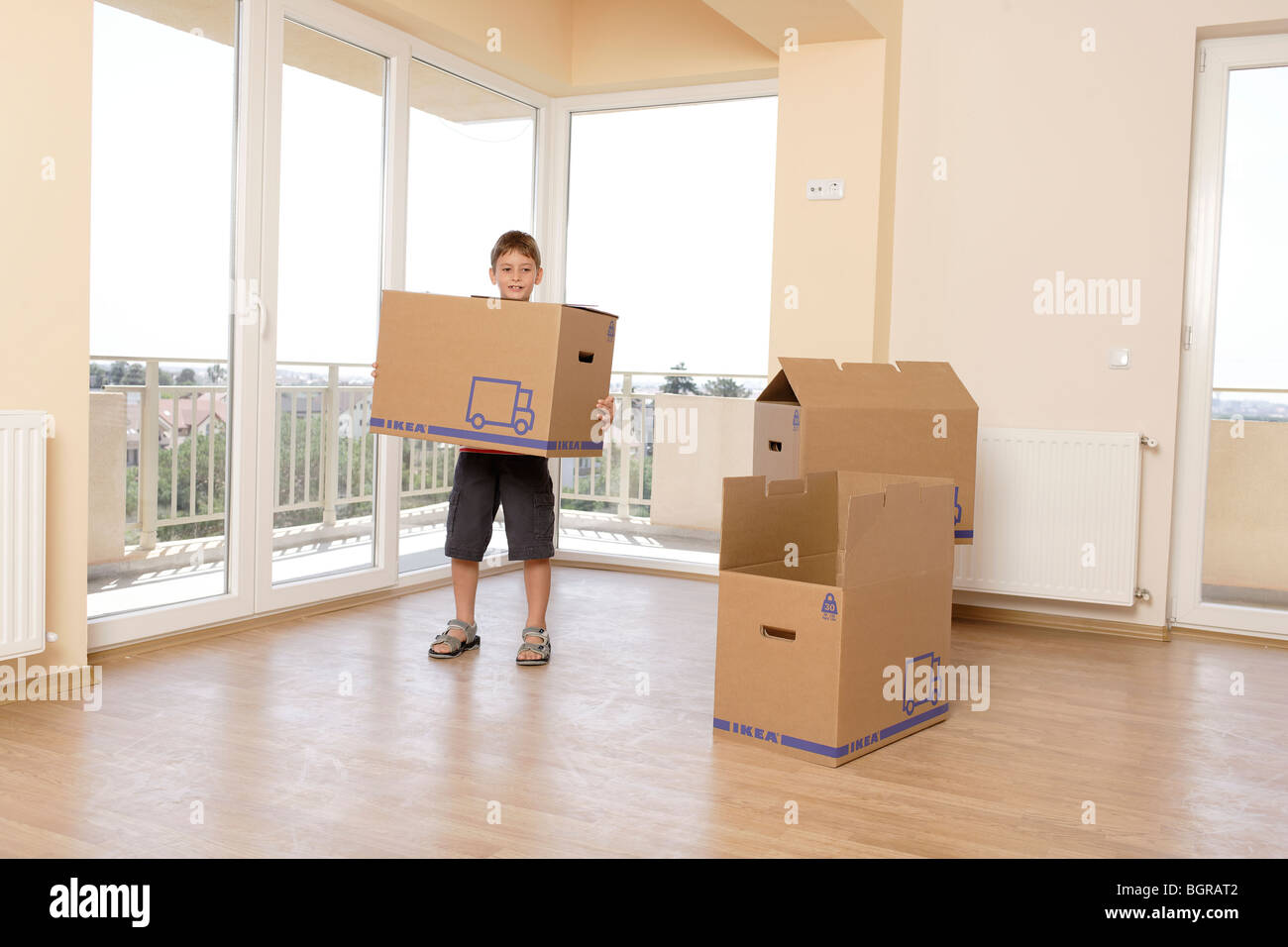 Bambino che trasportano grandi scatole in un vuoto non decorato appartamento Foto Stock