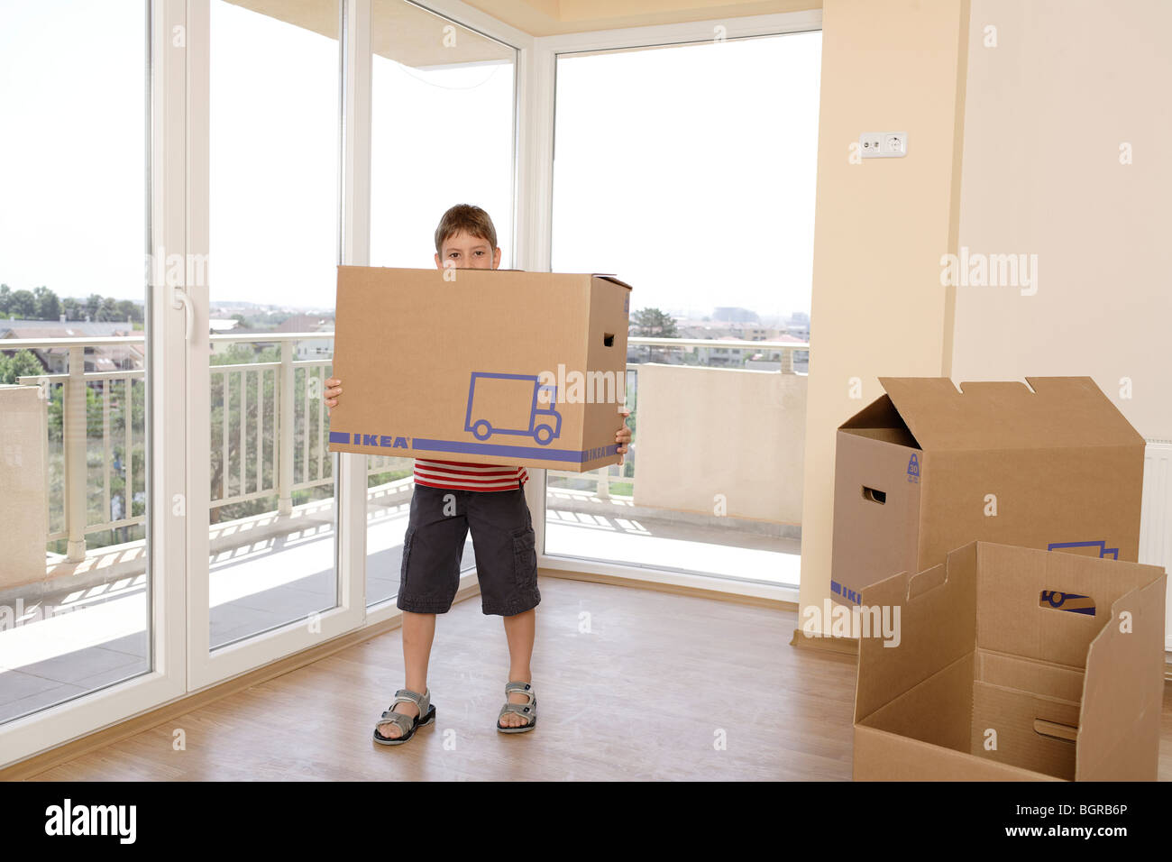 Bambino che trasportano grandi scatole in un vuoto non decorato appartamento Foto Stock