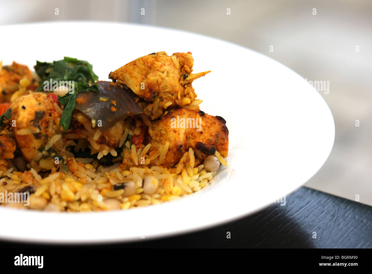 Fresh North Indian Achari Pollo al Curry spiedini con riso pilaf e Raita di cetriolo con nessun popolo contro uno sfondo nero Foto Stock
