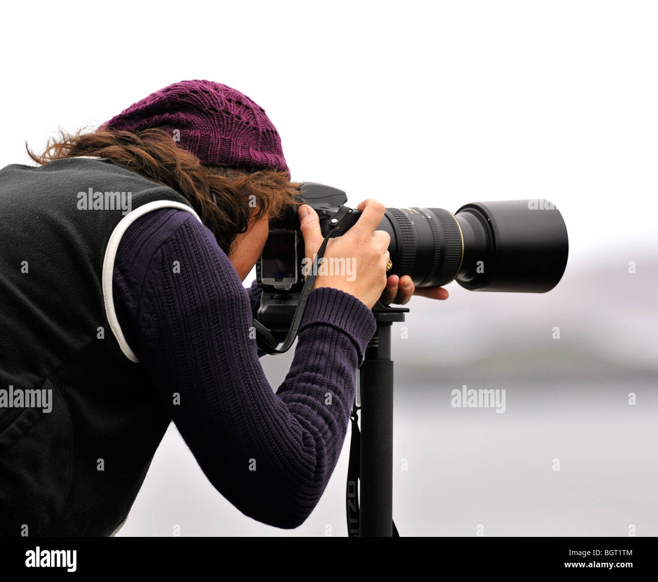 Fotografo femmina tenendo fotografia utilizzando high end fotocamera digitale con un lungo teleobiettivo e monopiede. Foto Stock