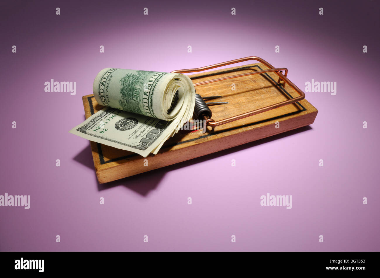 Un rotolo di soldi seduto su un legno armate mousetrap Foto Stock